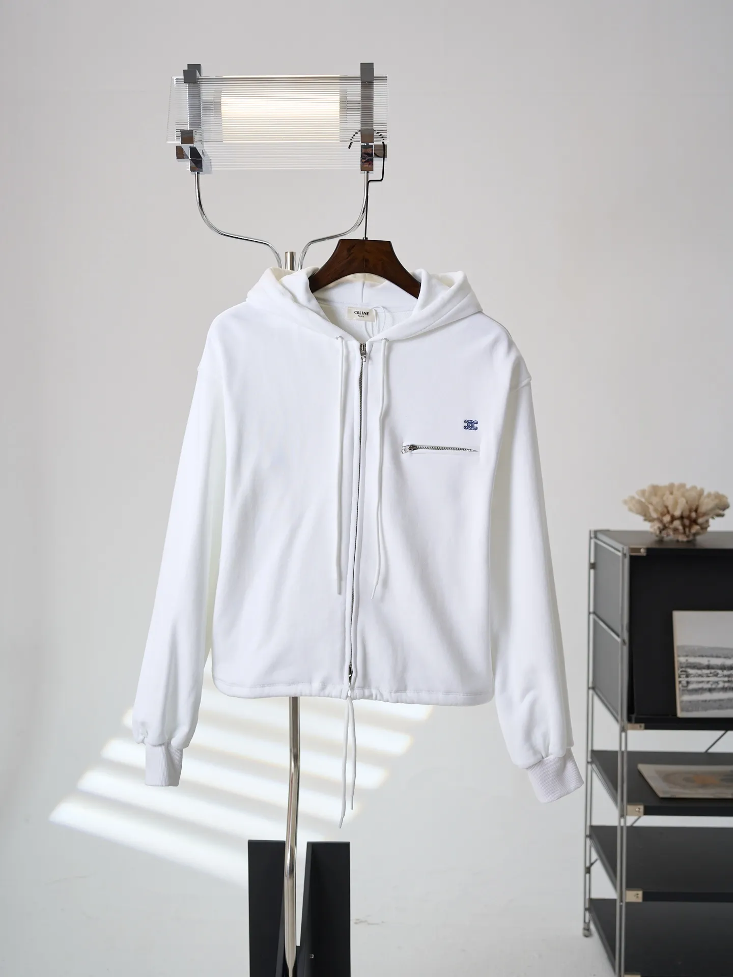 [Real auction] Celine/Celine logo embroidered zipper jacket (women's style) [In Stock] S M L custom-made light oxygen cotton-feel fleece knit, delicate and smooth, soft and skin-friendly. The body is laid out in clear white, with a soft cotton-like texture and rich layers. The elegant white tone brings a refreshing and clean daily atmosphere. The iconic Celine Arc de Triomphe embroidery is embellished on the chest, which is simple yet memorable. The simple hoodie silhouette sets a refreshing tone, and the two-way metal zipper design is full of texture. The short silhouette with loose, dropped shoulders gently modifies the lines of the shoulders and arms; the drawstring at the hem is adjustable to shape the silhouette as desired, and the short length optimizes body proportions. The simple silhouette carries a lazy atmosphere, and the relaxed outfit reveals the French girlish attitude. 1. Imported machine embroidery technology uses advanced computer control systems and precision mechanical components to precisely create the iconic TRIOMPHE logo embroidery, with smooth and delicate lines and a full sense of sophistication. 2. Fermentation washing treatment: The fabrics have been fermentation washing, which makes the hand feel and texture better, is not easy to deform, shrink, and fade, and maintains long-term beauty and loose fit.
